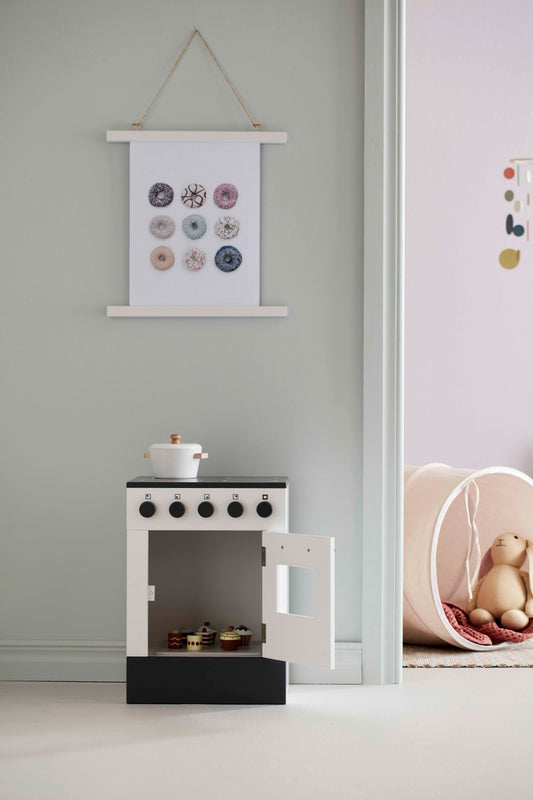 White wooden toy stove with the oven door open in a Scandi-style playroom