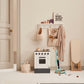 White wooden toy stove in a play corner with a toy vacuum cleaner