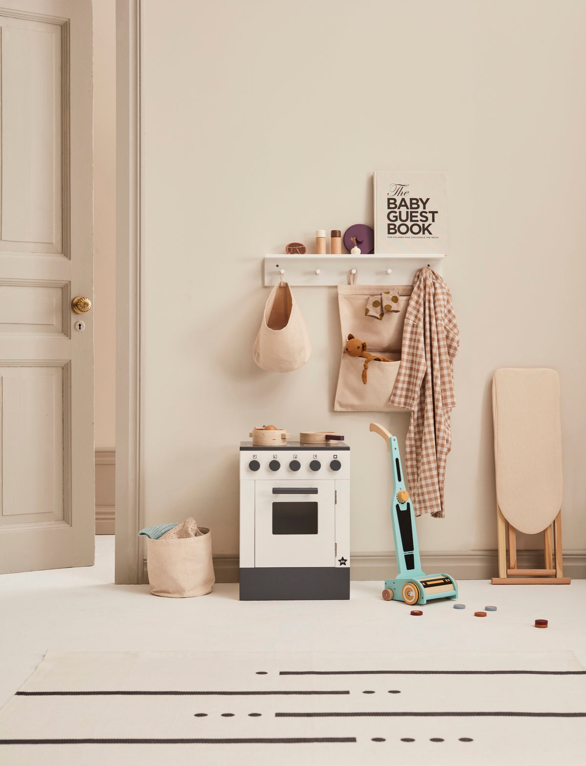 White wooden toy stove in a play corner with a toy vacuum cleaner